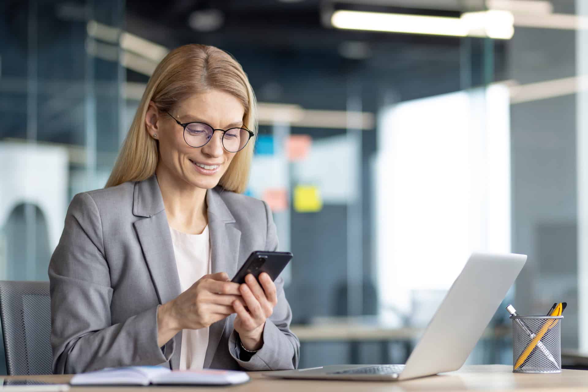 Businesswoman using smartphone in modern office for recruitment.
